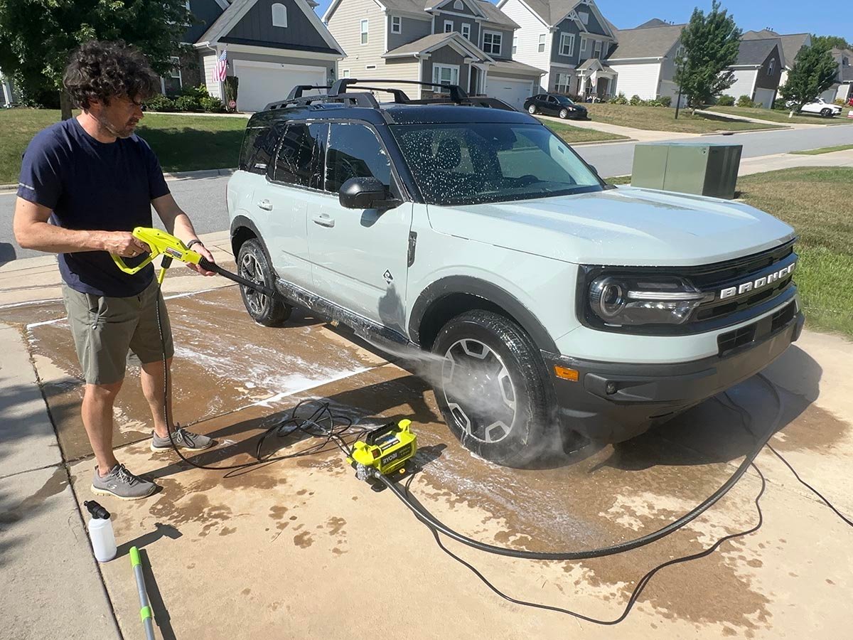 A product tester using one of the best ryobi pressure washers to wash a car tire
