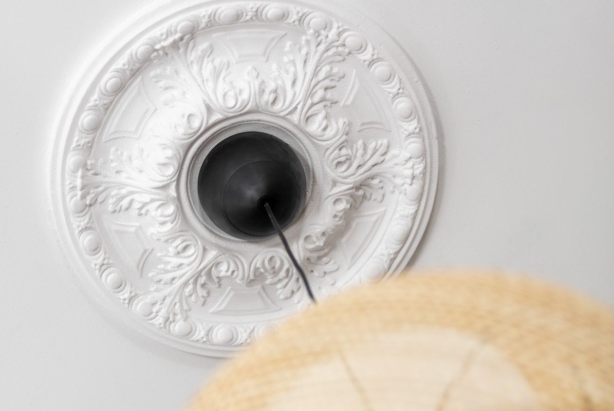 View of an antique ceiling medallion from the ground up, a hanging light pendant dangling from ceiling.
