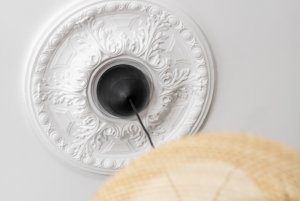 View of an antique ceiling medallion from the ground up, a hanging light pendant dangling from ceiling.