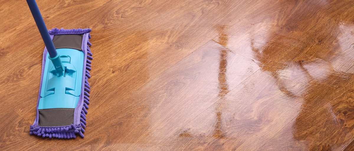 Someone using a microfiber mop to clean laminate floors.