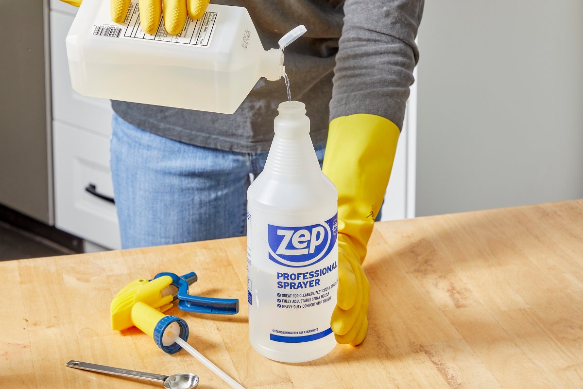 Woman pours rubbing alcohol into a spray bottle to make a mixture.