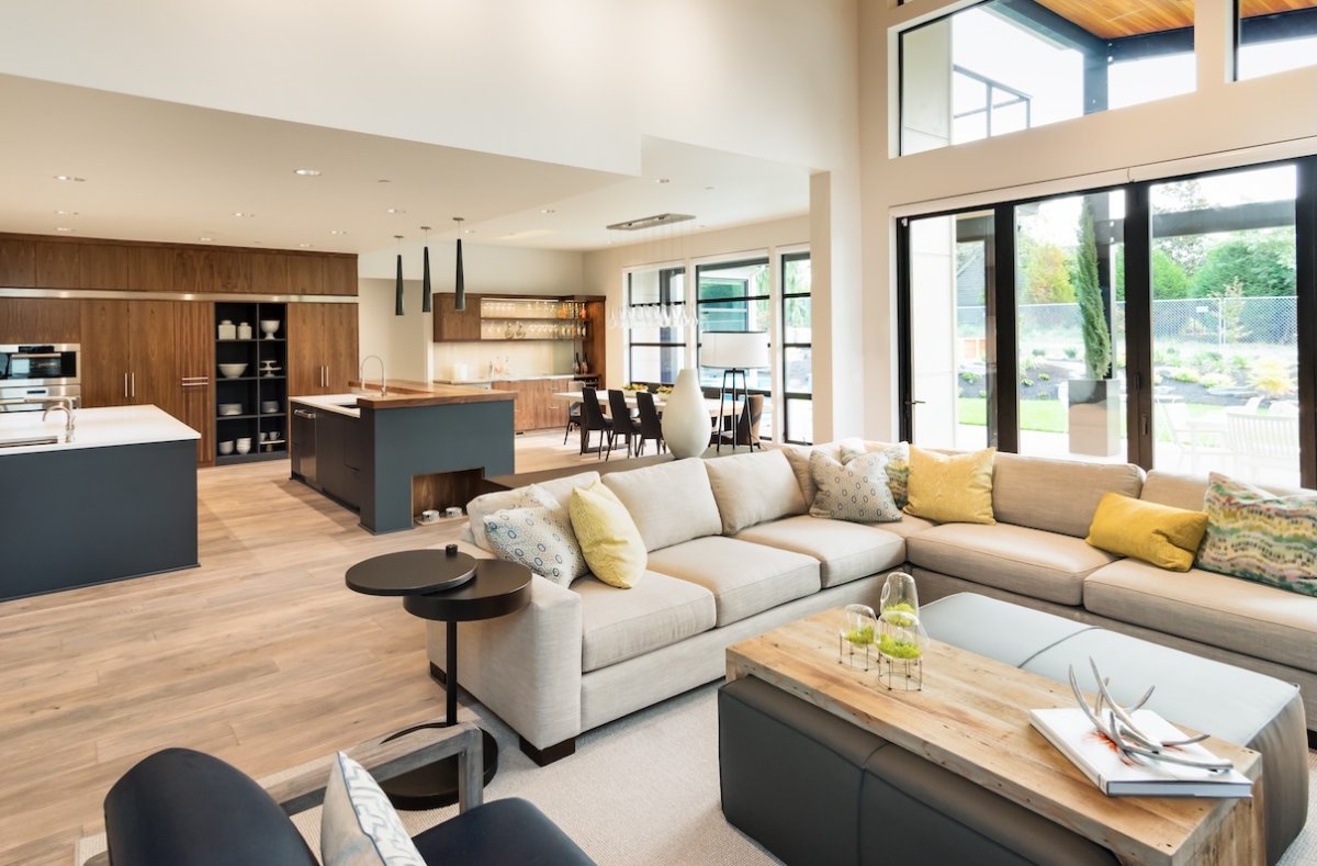 Home interior with hardwood floors and open floorplan showing dining room, kitchen, and living room. Has high vaulted ceilings.