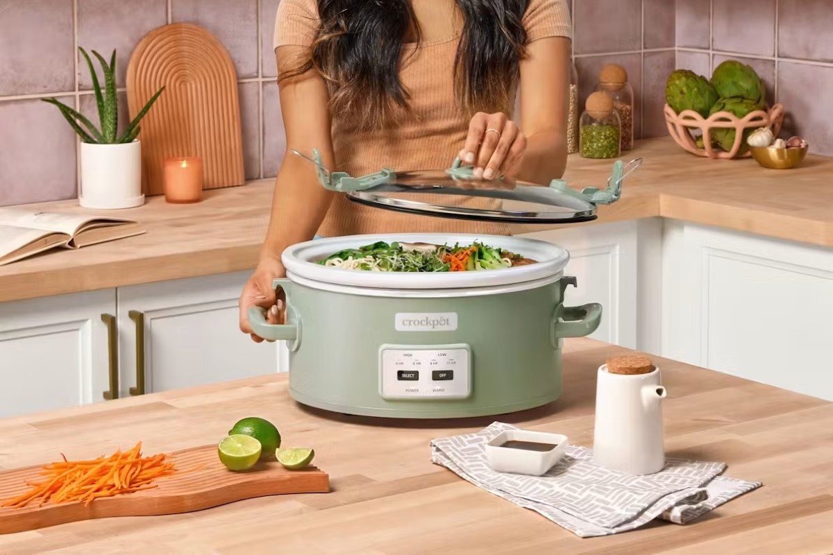 A person is opening the crock pot full of food.