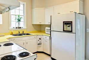 old dated kitchen with white appliances and yellow counters