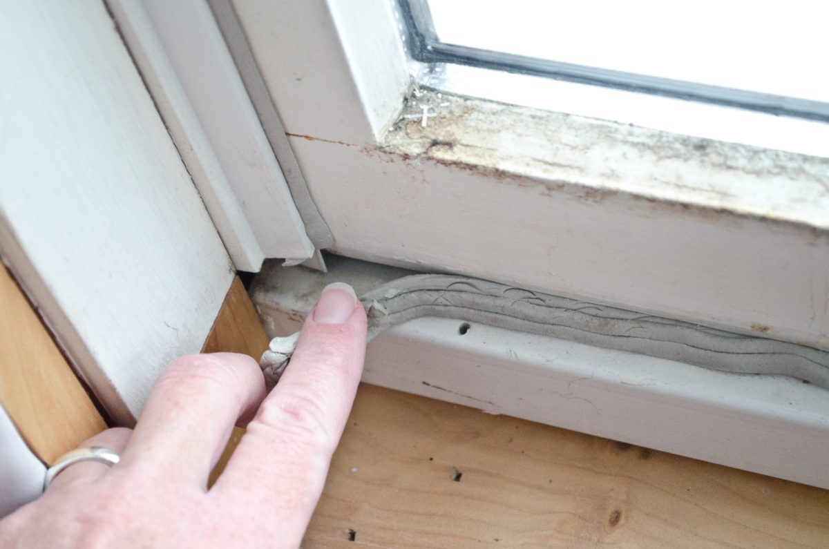 Finger touching deteriorating caulk.