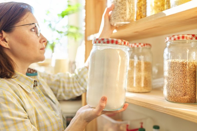Woman holding a glass container filled with flour in her pantry
