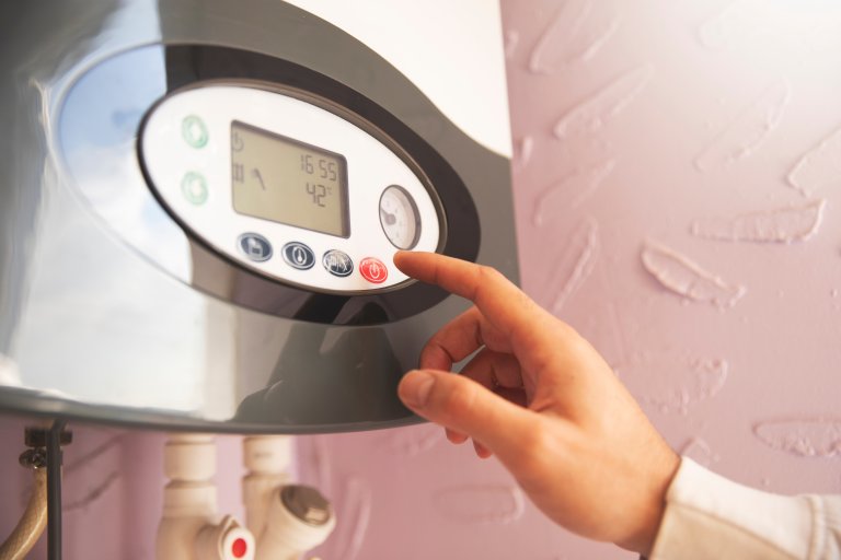 Hand adjusting the temperature of a water heater.