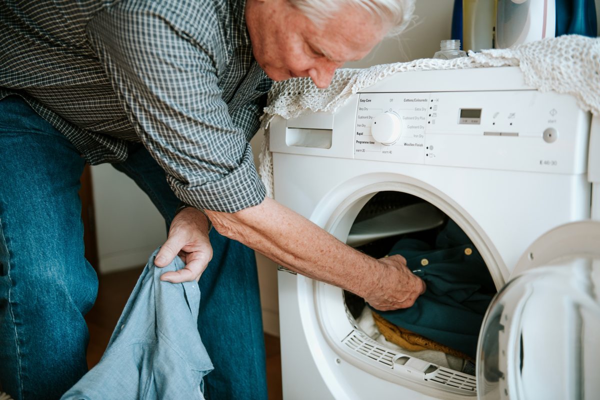 Man loading clothes into a washing machine.