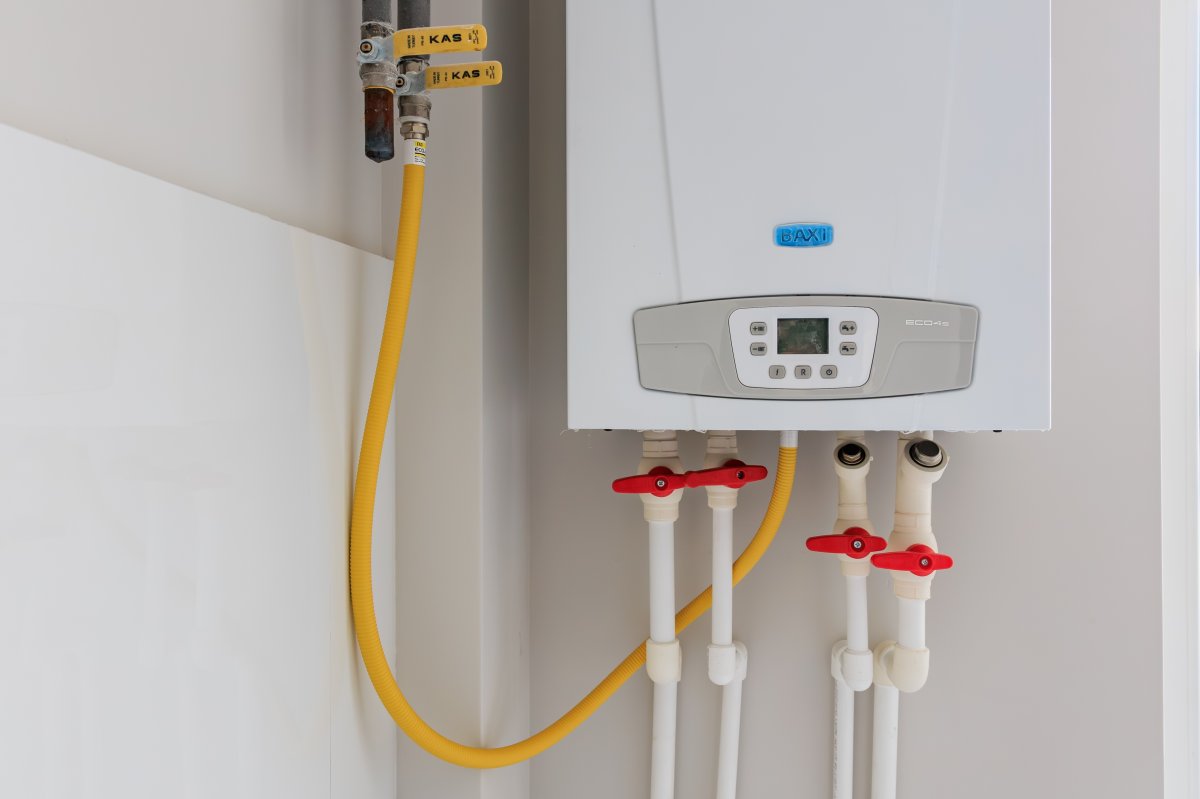 Modern tankless gas water heater with yellow gas line in utility room.