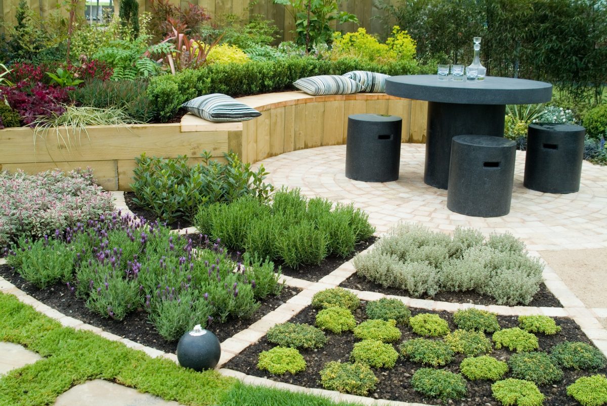 Inviting garden featuring a contemporary table and seating area surrounded by vibrant plants and fresh herbs.