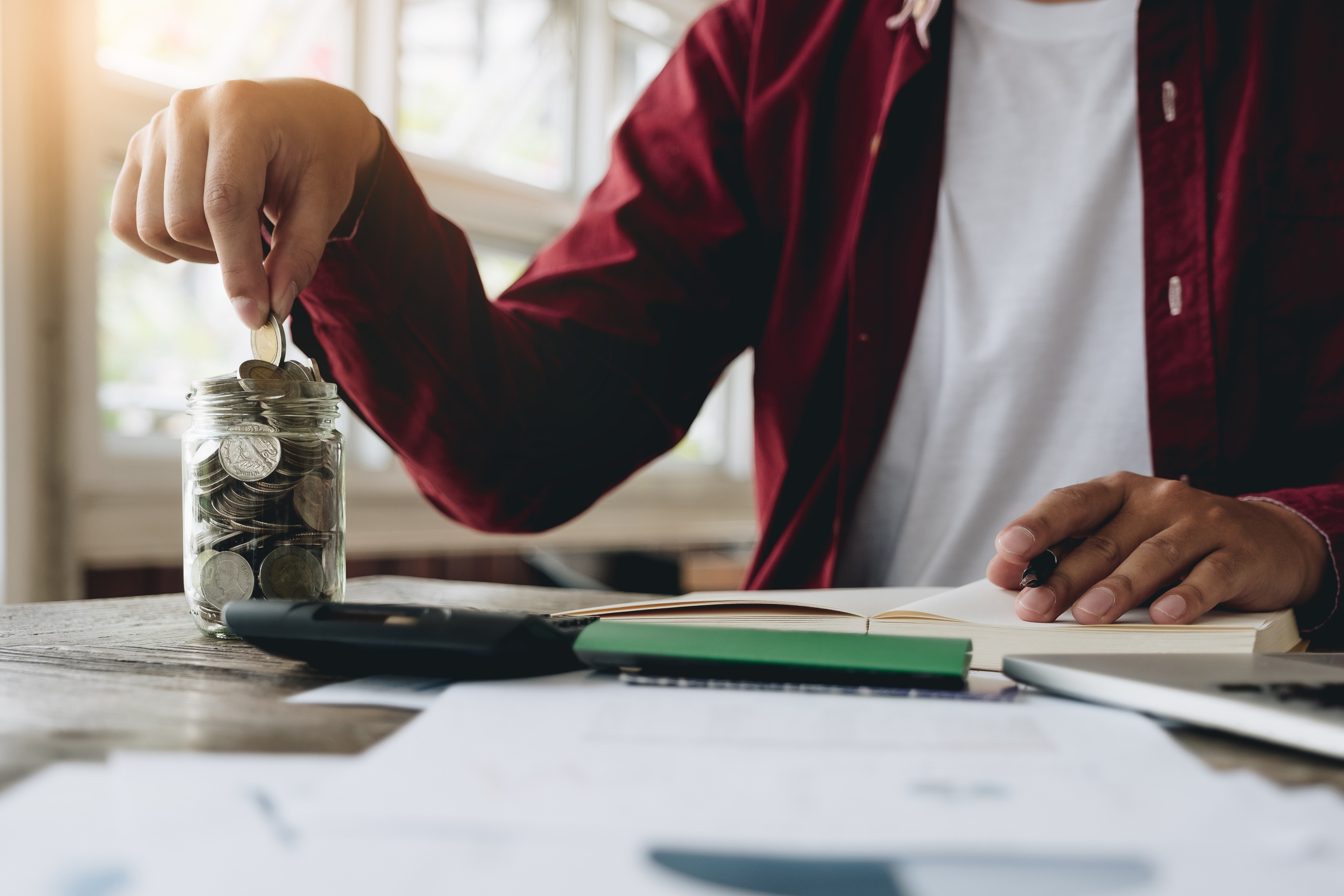 business man saving money with putting coin in glass and calculating for financial saving, finance accounting concept