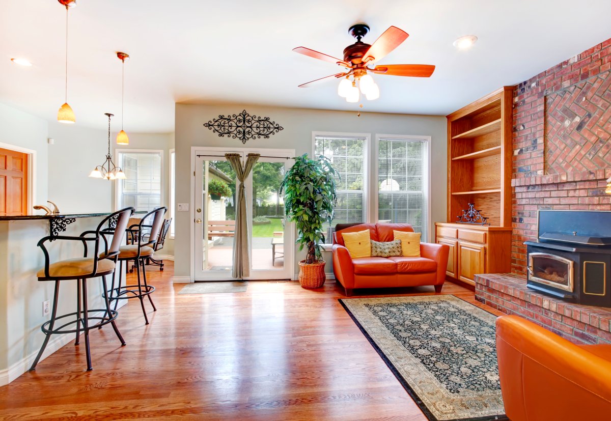 Luxury living room with brick wall and antique stove. View of leather love seats. Room decorated with fake tree in a wicker pot