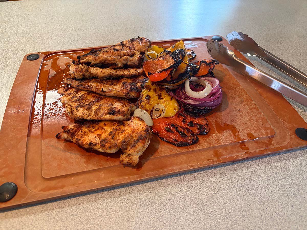 Cooked chicken and vegetables off the Monument Grills G22 Stainless Tabletop Propane Grill