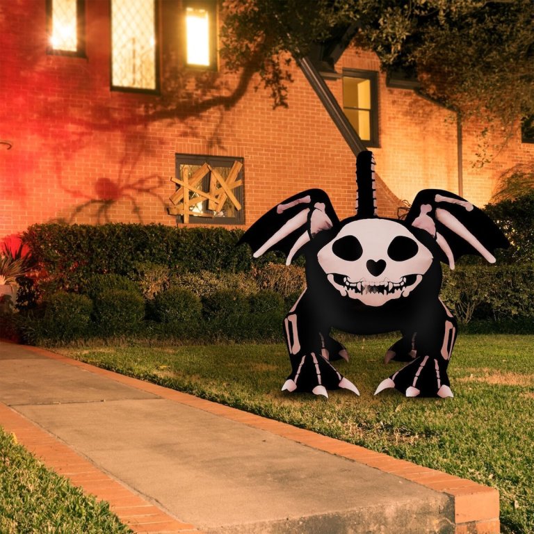 The Haunted Hill Farm 5.9-Foot Inflatable Skeleton Cat next to a walkway in a spooky yard