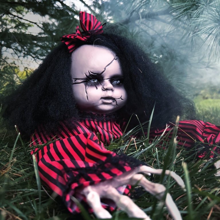 The Haunted Hill Farm Animatronic Haunted Crawling Baby Doll crawling along the grass under a tree