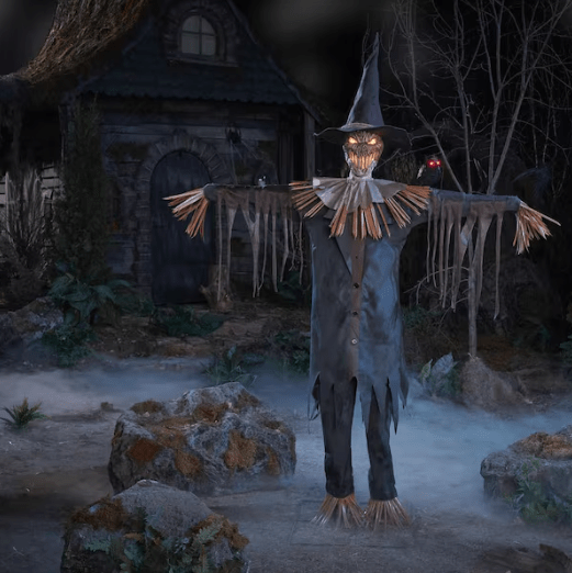 The Home Accents 6.5-Foot Animated LED Stalking Scarecrow in a foggy yard with a spooky house in the background