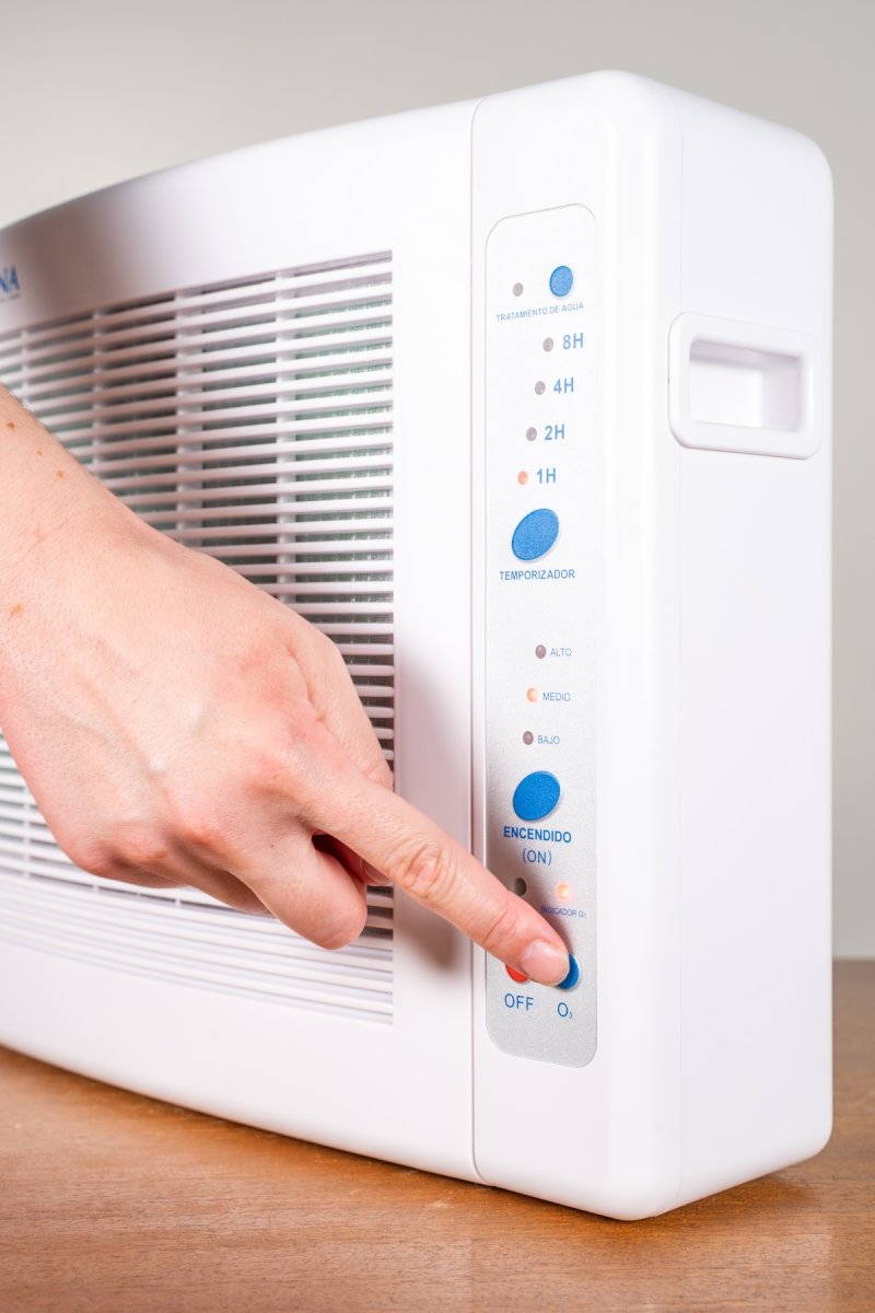 A hand presses buttons on an ozone machine.