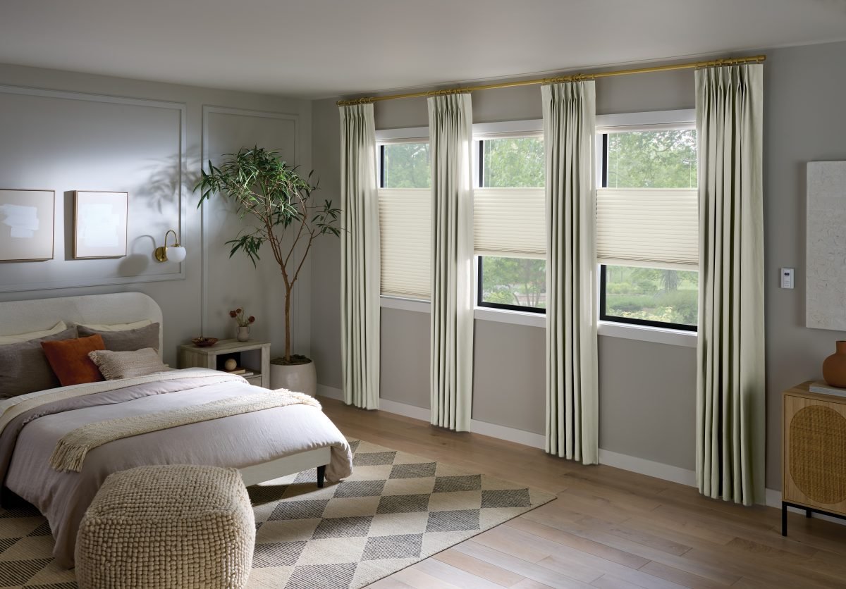 Modern gray and pale yellow bedroom with cellular shades paired with drapery panels
