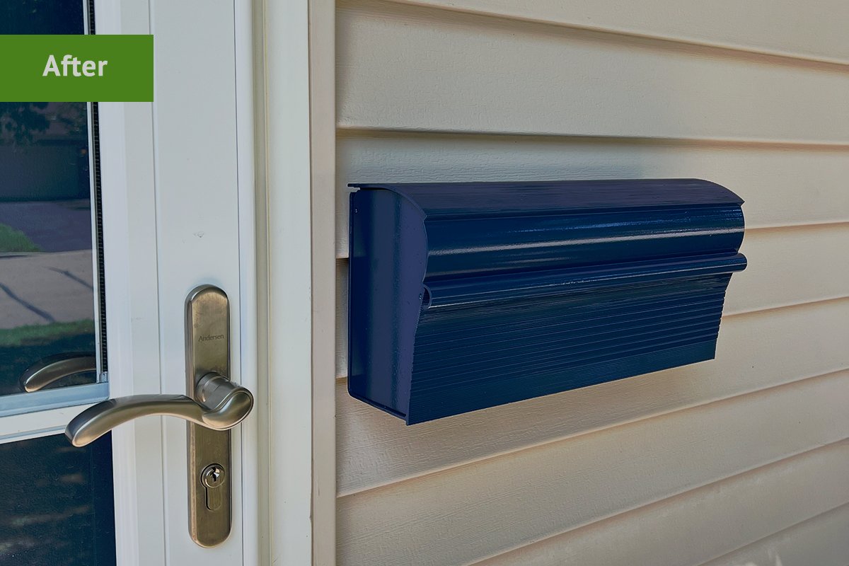 An after shot of a newly painted mailbox mounted on a house.
