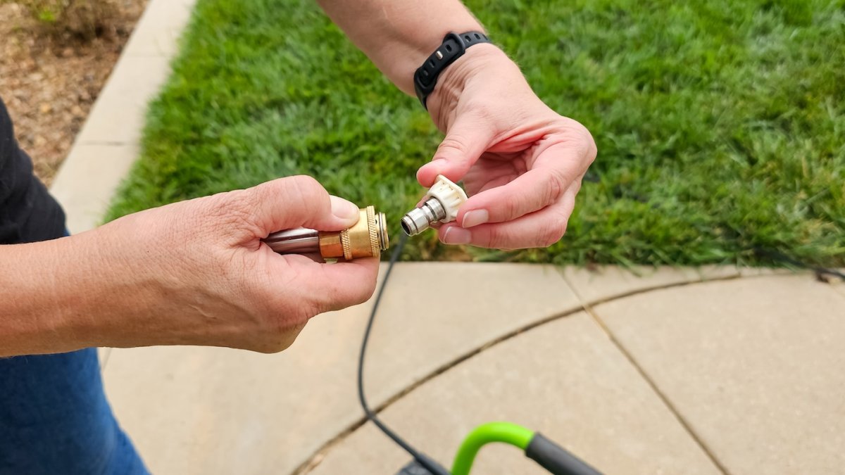 Man attaches a nozzle to a pressure cleaner wand.