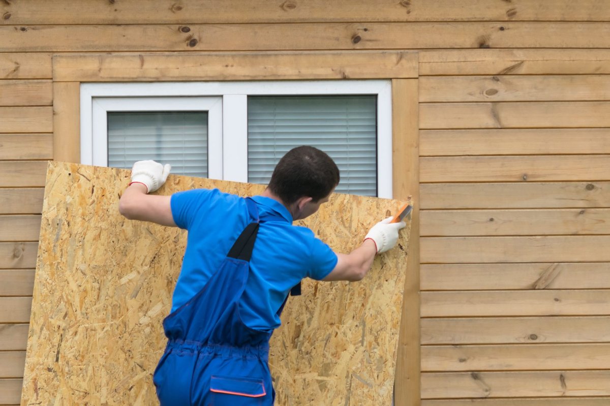 Man puts up plywood on a window before a storm
