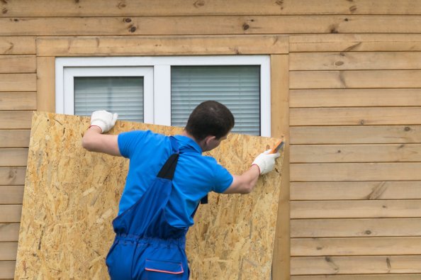 Man puts up plywood on a window before a storm