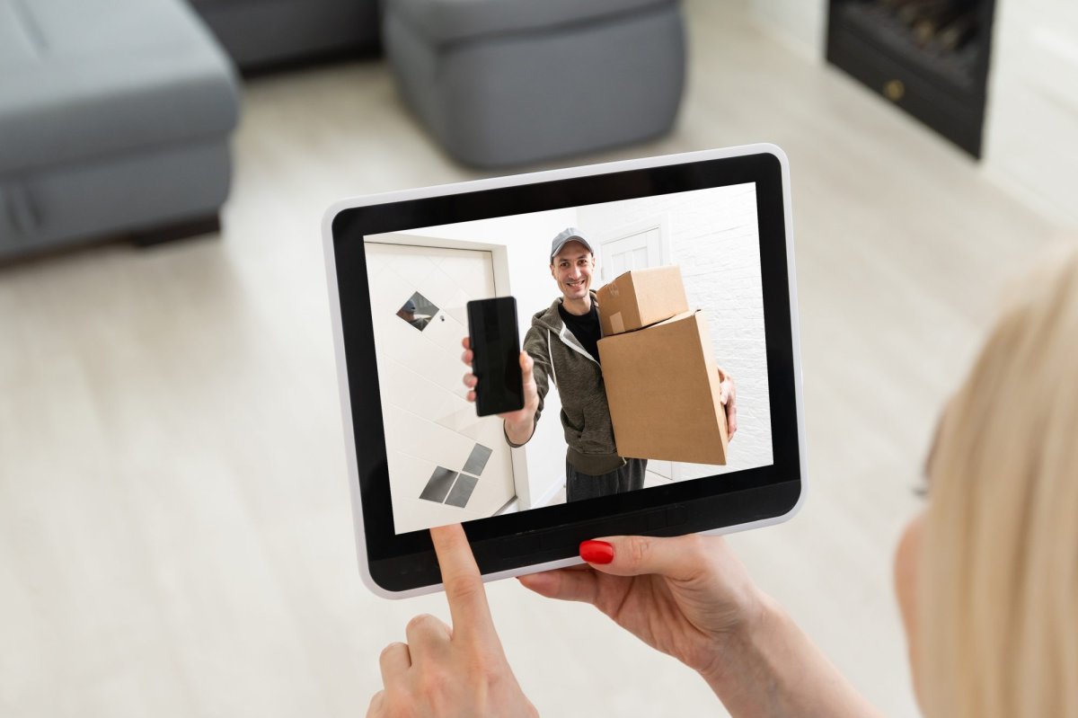 A delivery man rings the doorbell on the monitor of the security camera.