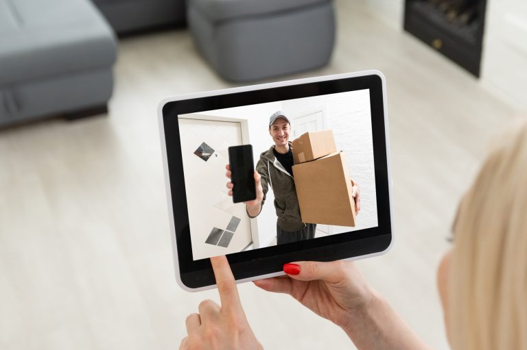 A delivery man rings the doorbell on the monitor of the security camera.