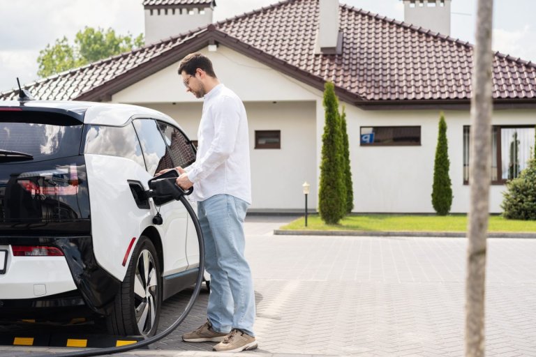 Man charging an electric car at home In his driveway.