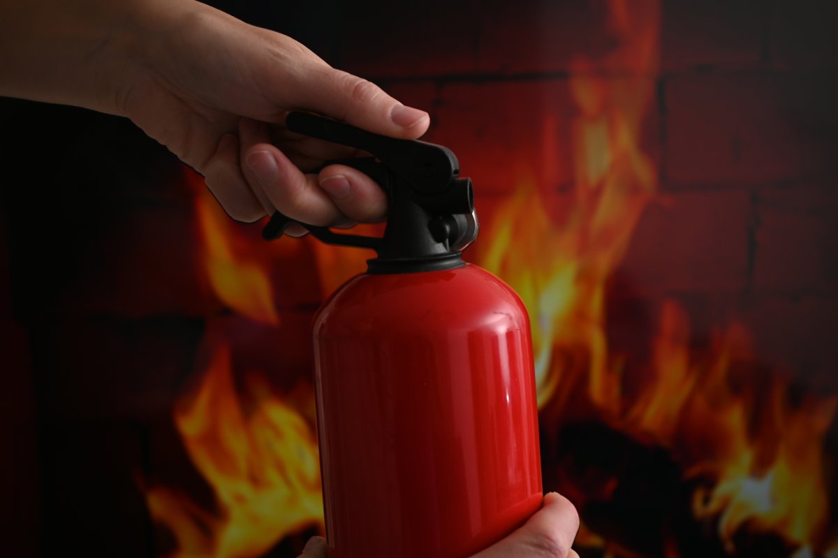 Person holding a fire extinguisher in front of a fireplace.
