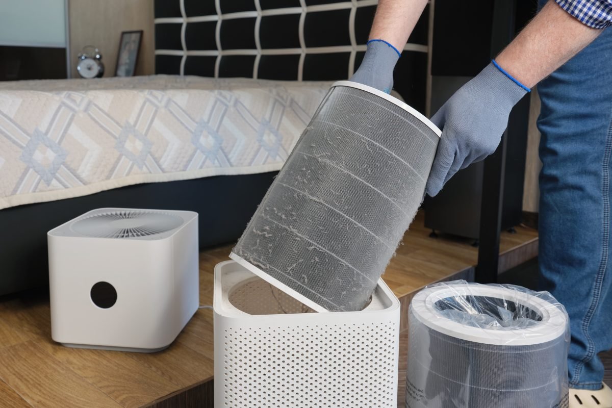 A man in gloves changes a dirty air filter in an air purifier