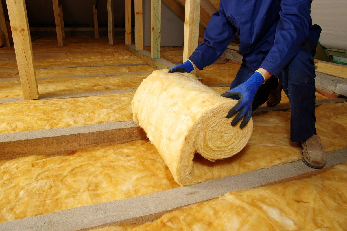 A person is using rolled insulation in the attic. 