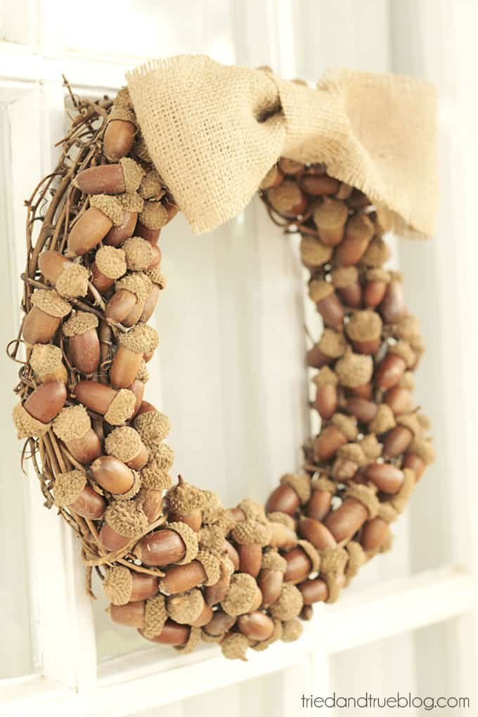 A DIY wreath covered with acorns and tied with a burlap bow.