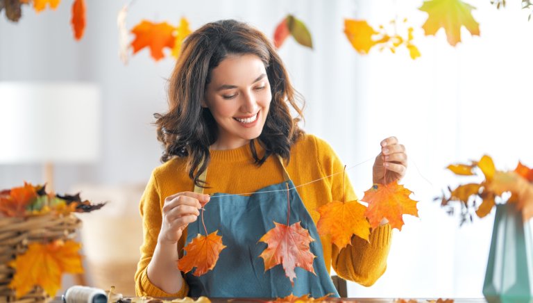 Happy woman making a fall banner out of leaves.