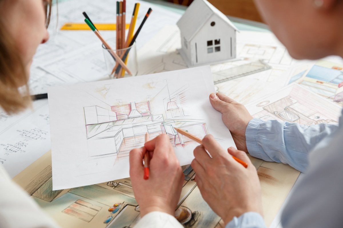 Interior designers examining color hand drawings of a kitchen design.