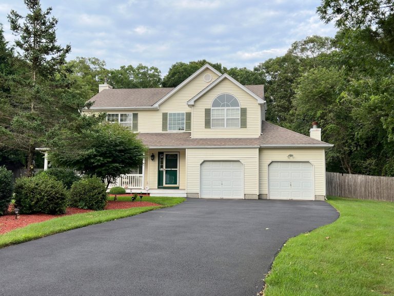 Large, contemporary house with attached, two-car garage and asphalt driveway.