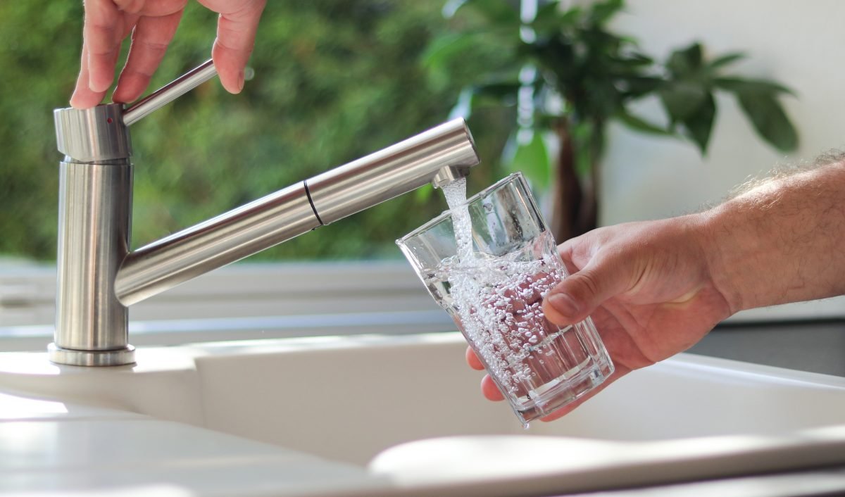Close up of male hands filling a glass with water from a filtered faucet