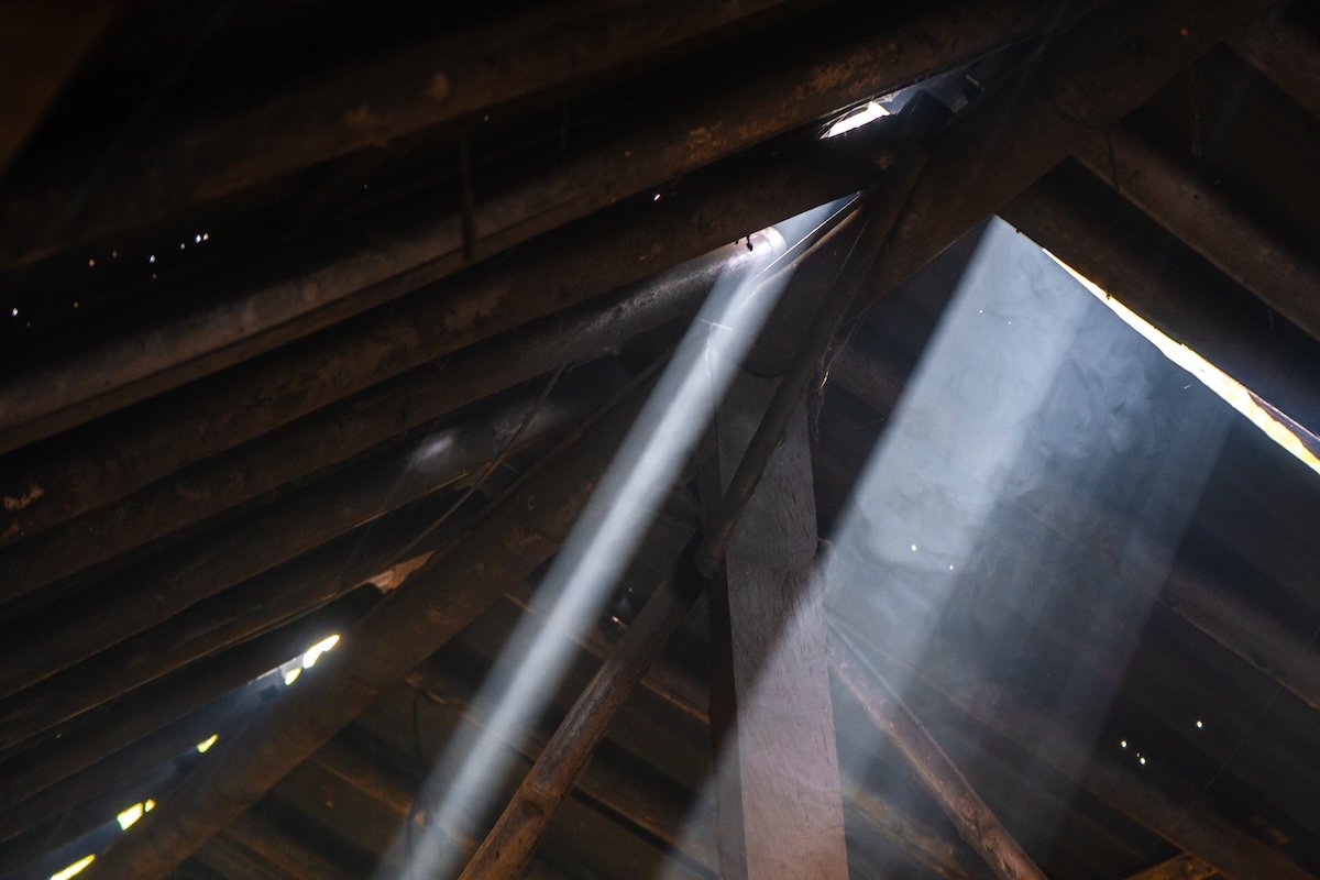 Sunbeam coming through wood slats in attic roof.