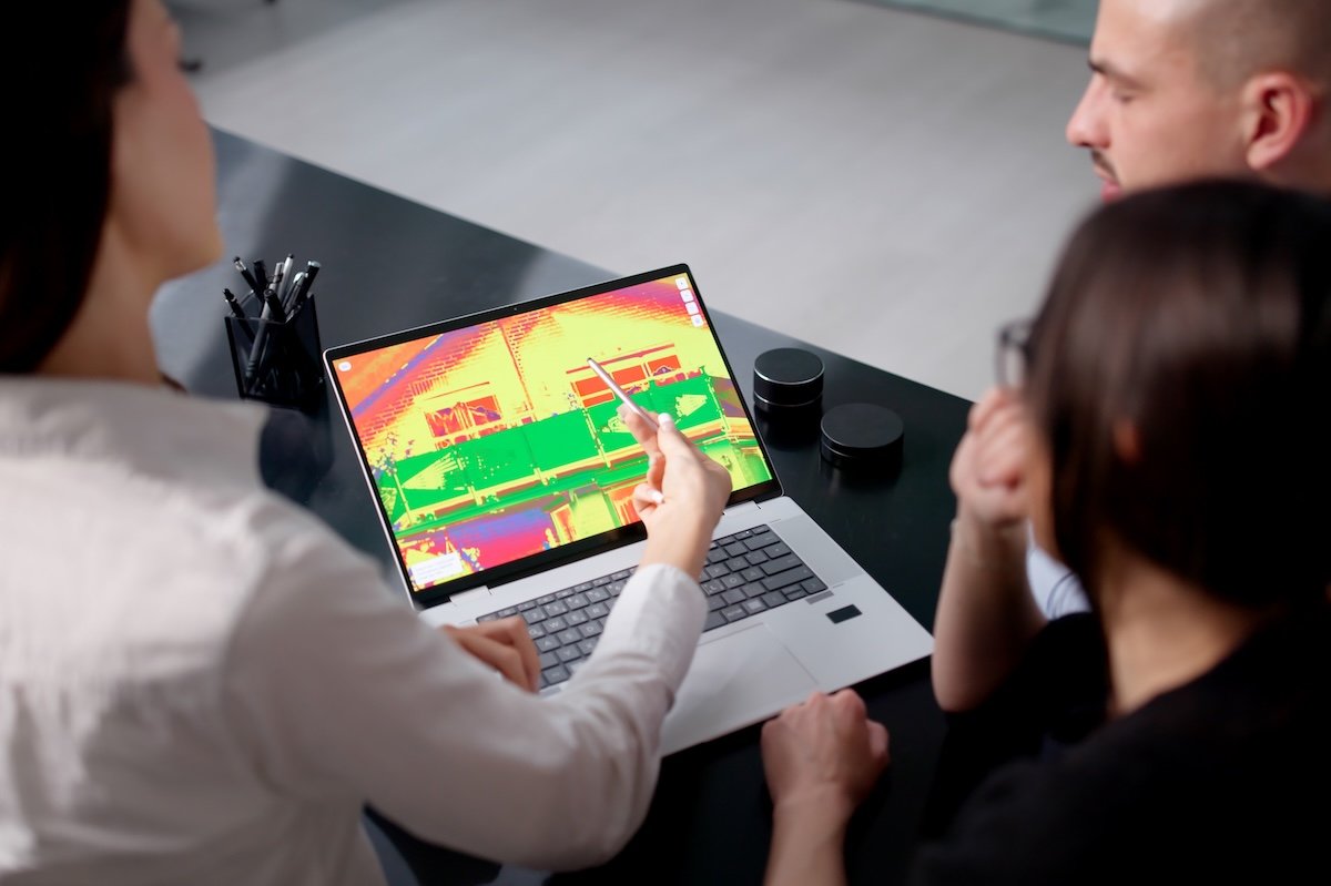 Energy efficiency auditor shows couple a home thermography image on a computer screen.
