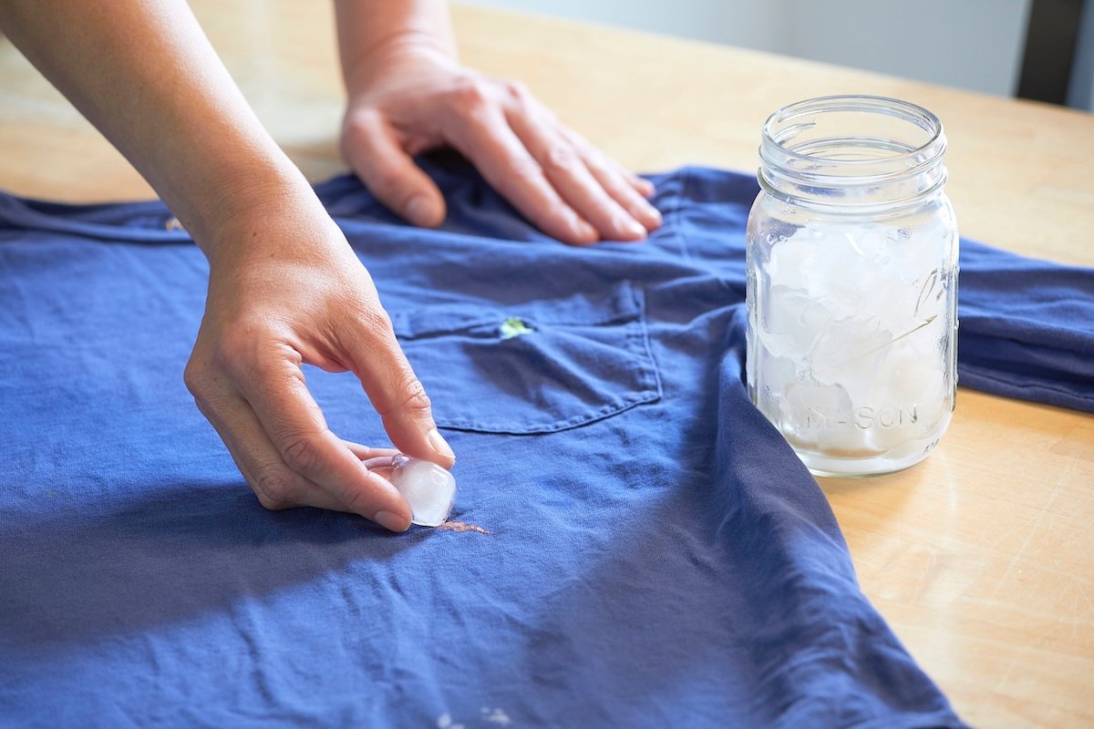 Woman uses ice cubes to remove a stain from a blue T-shirt.