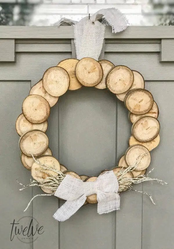 A DIY wreath made of wood circles hangs from a front door.