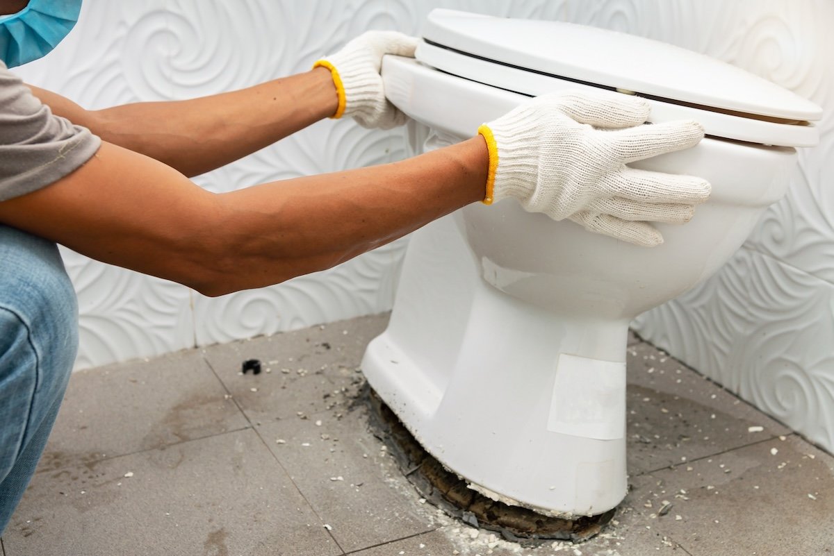 A DIYer replacing a toilet wax ring. 