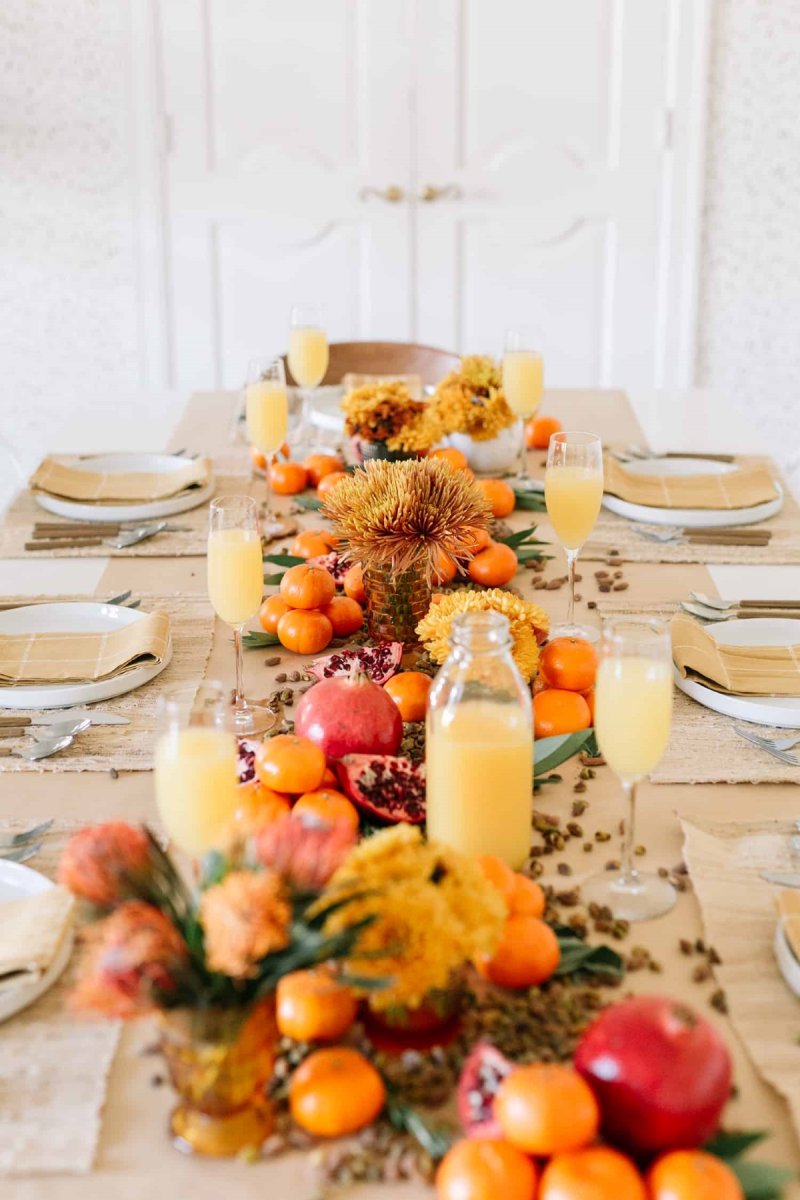 A beautiful table center piece decorated with candles and fruit.