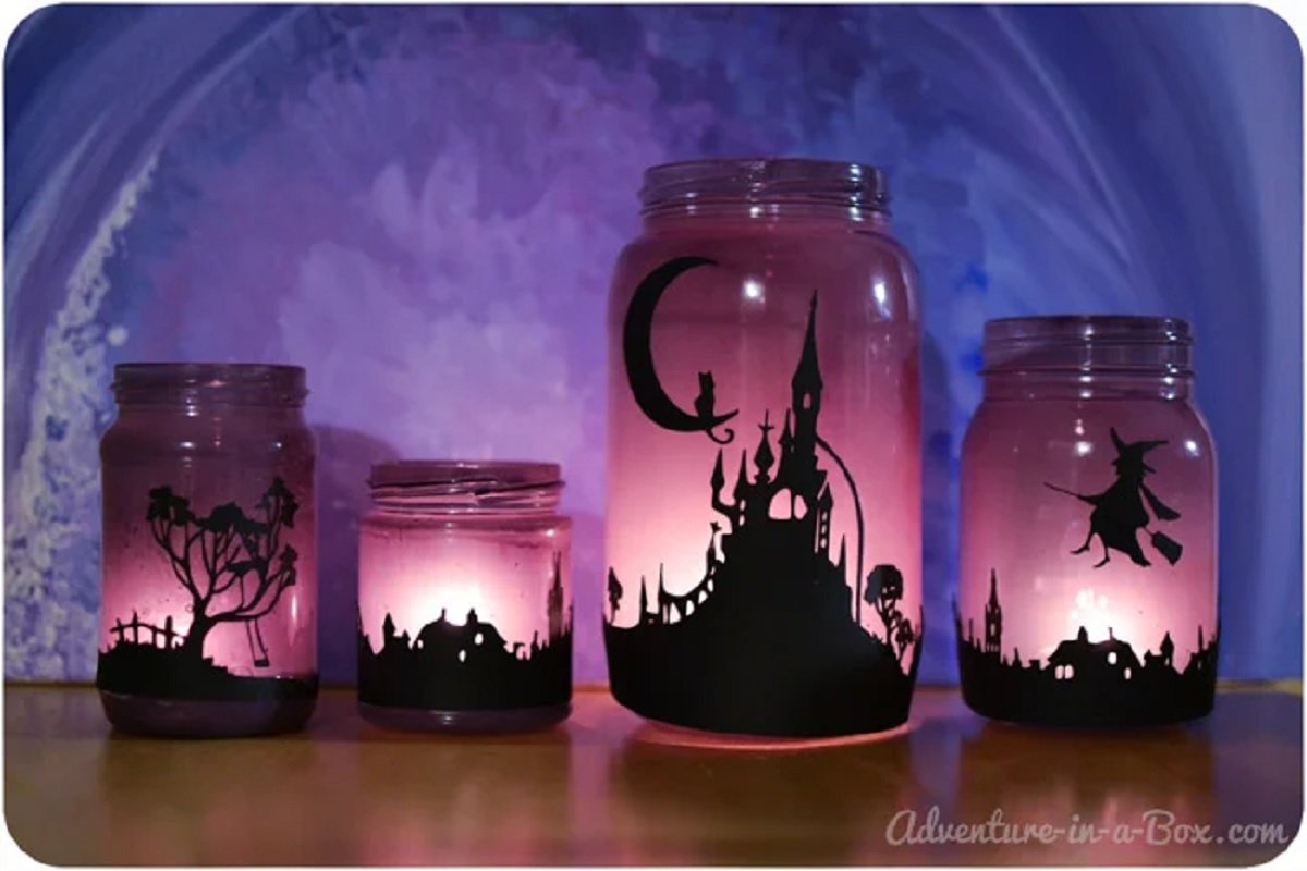 Four Halloween decorated jars with glowing lights.