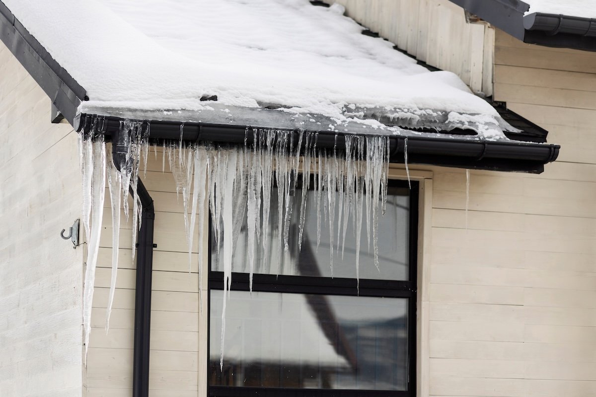 Rain gutters on a modern home filled with icicles and snow.