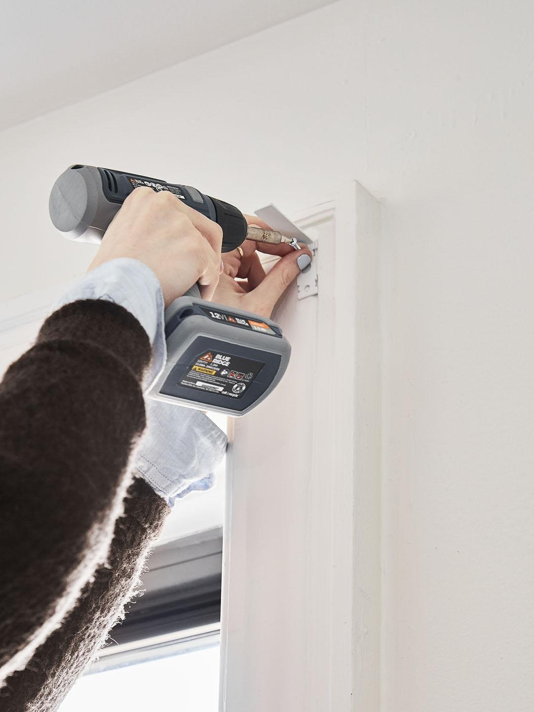 Using a drill to install hardware on a door frame