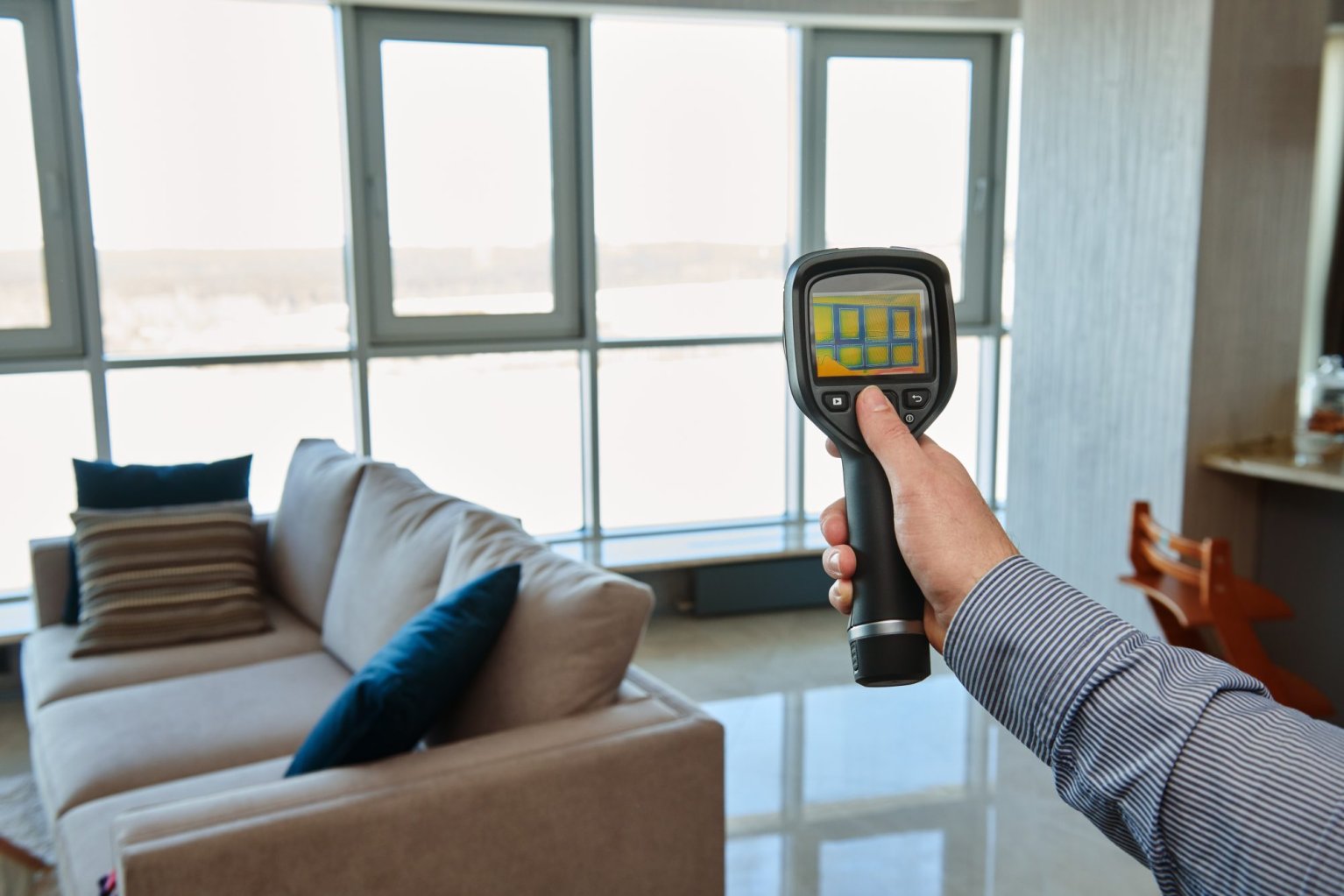 Person holding thermal imaging camera at near window