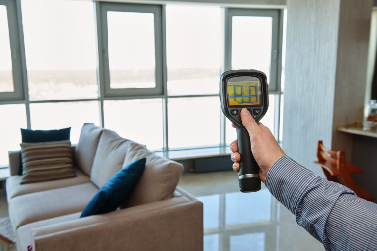 Person holding thermal imaging camera at near window