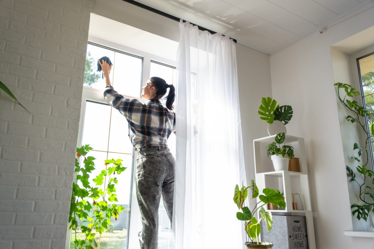 Woman washes a window inside using a rag